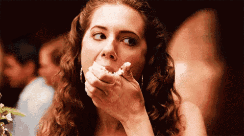 a woman with curly hair is eating a piece of food with her hand .