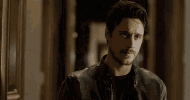 a man with a beard wearing a black leather jacket