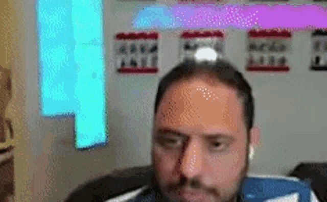 a man with a beard and headphones is sitting in front of a computer monitor .