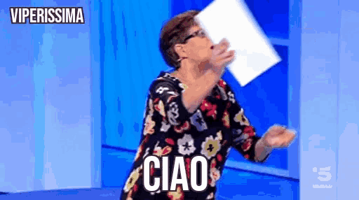 a woman is holding a piece of paper in her hand and says ciao .