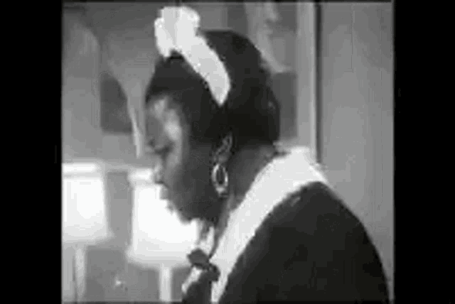 a black and white photo of a woman wearing a maid costume and earrings .