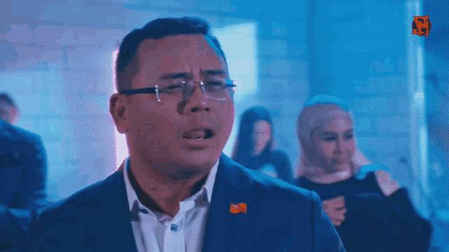 a man in a suit has a red pin on his lapel that says ' w ' on it