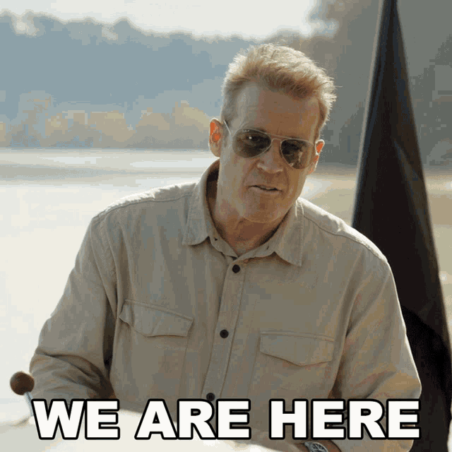 a man in a tan shirt and sunglasses says we are here