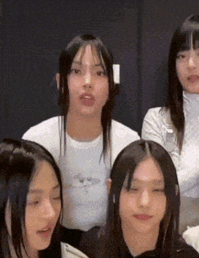 a group of young women with their eyes closed and one wearing a white shirt with a butterfly on it