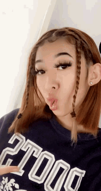a girl wearing a blue shirt that says ' dolls ' on it is making a funny face .