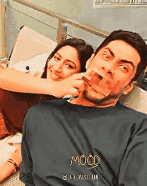 a man and a woman are posing for a picture and the man is wearing a mood sweatshirt