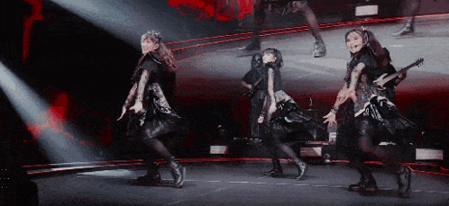 a group of girls are dancing on a stage and one of them is playing a guitar .