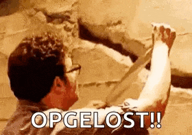 a man is holding a piece of wood in his hand and says opgelost .