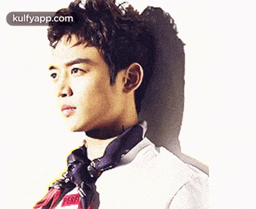 a young man wearing a white shirt and a tie is looking to the side .