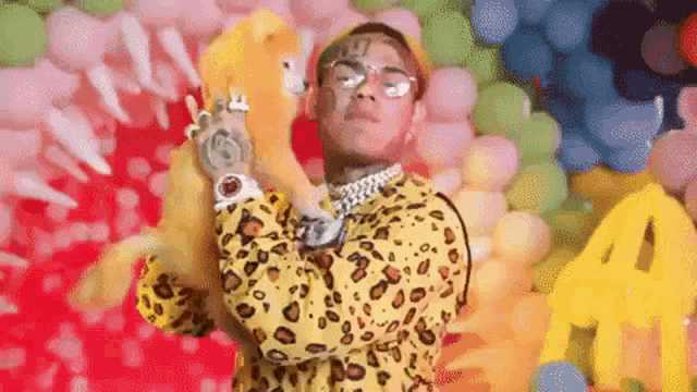 a man in a leopard print shirt is standing in front of balloons .