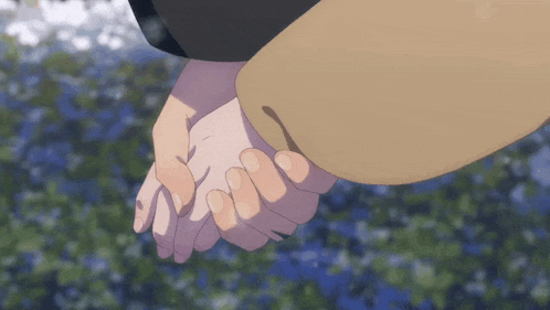 two people holding hands in front of a field of flowers