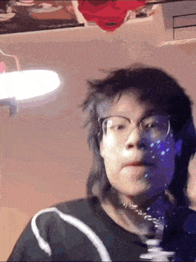 a person wearing glasses and a choker is standing in front of a mirror