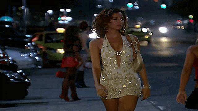 a woman in a white dress is walking down a street