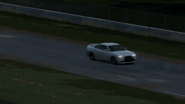 a white dodge charger is driving down a road