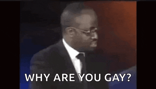 a man in a suit and tie is talking into a microphone while asking why are you gay .