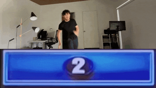 a man in a black shirt is standing in front of a blue button with the number two on it