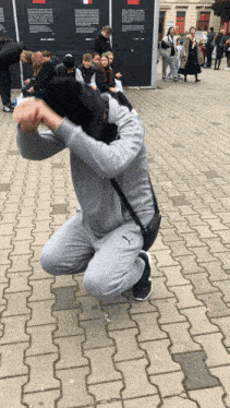 a man in a grey puma sweatshirt kneeling down