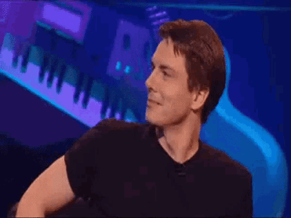 a man is laughing with his mouth open in front of a piano