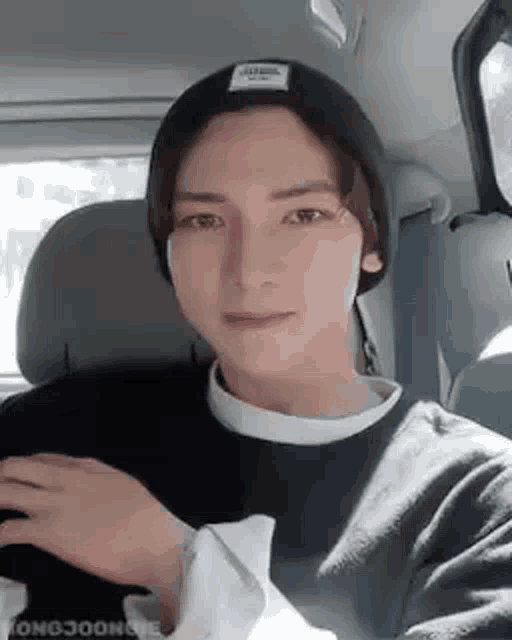 a young man wearing a beanie and a sweater is sitting in a car .
