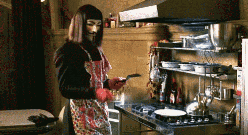 a man wearing a mask and an apron is cooking in a kitchen