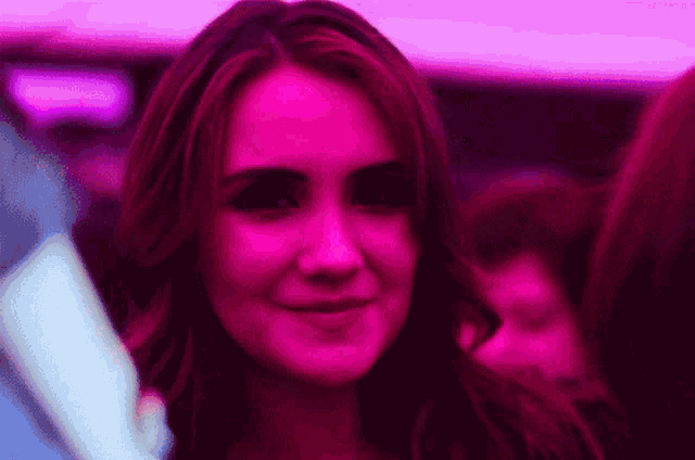 a woman with red hair is smiling in a pink light