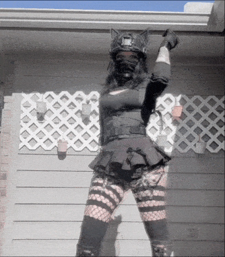 a woman wearing a cat ear helmet is standing in front of a white lattice wall