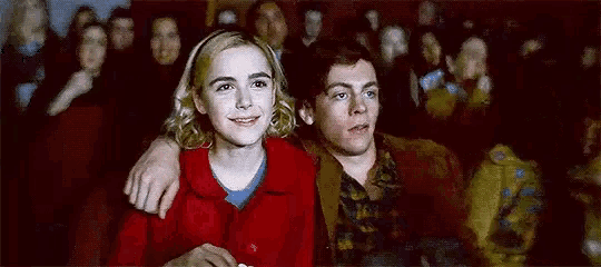 a man and a woman are sitting next to each other in a movie theater watching a movie .