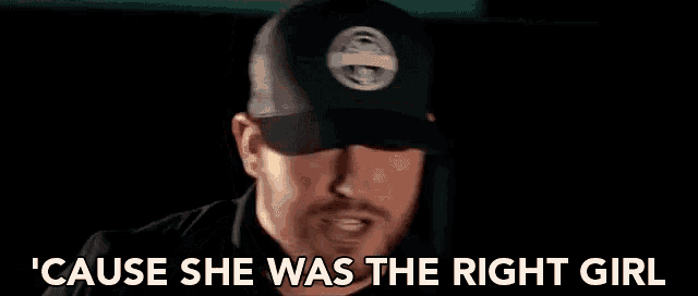a man with a beard is wearing a baseball cap and talking .