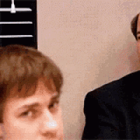 a man in a suit is looking at another man in a suit in a room .