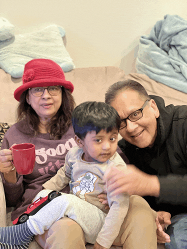 a woman wearing a good vibes sweatshirt sits on a couch with a man and a child