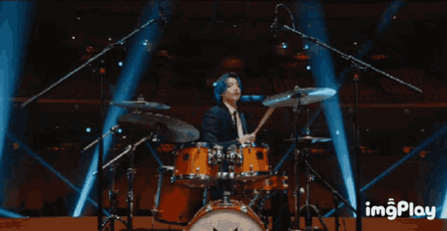 a man in a suit and tie is playing drums