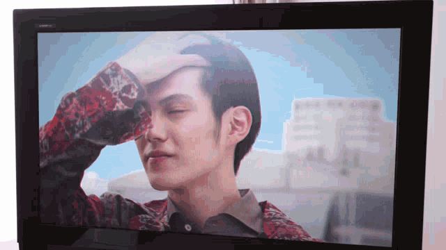 a man with his hand on his forehead is on a tv screen