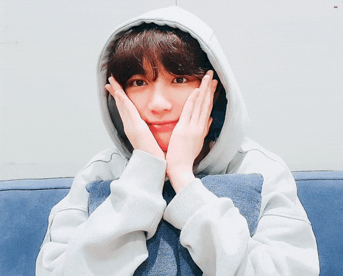 a young man wearing a white hoodie is giving a peace sign
