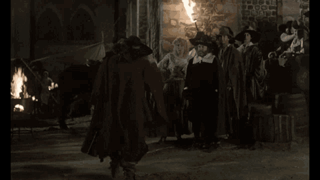 a group of people are standing around a fire