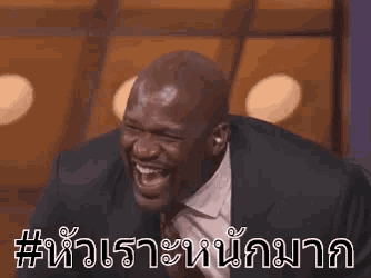 a bald man in a suit and tie is laughing with a foreign language .