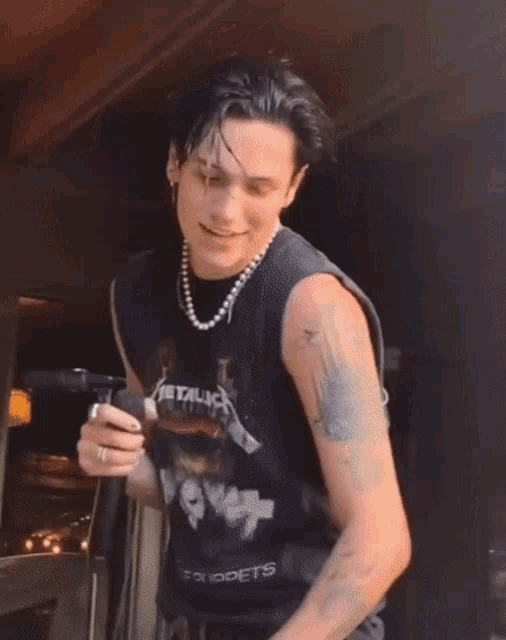 a man wearing a metallica shirt is holding a microphone