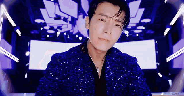 a man is wearing a blue sequined jacket and a necklace .