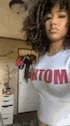 a woman with curly hair is wearing a white t-shirt with the word tom written on it .