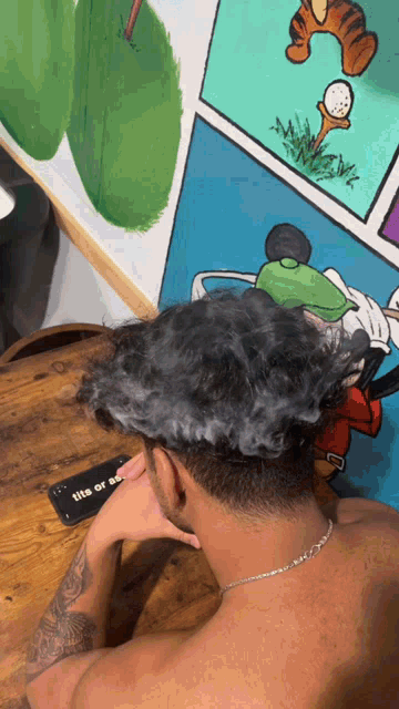 a man sitting at a table with smoke coming out of his head and a phone that says tits or so on it