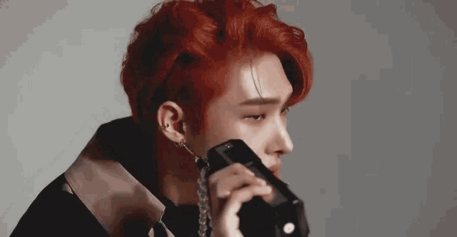 a man with red hair is holding a telephone in his hand .