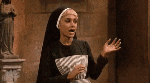 ariana grande is wearing a nun costume and making a funny face while standing in front of a statue .