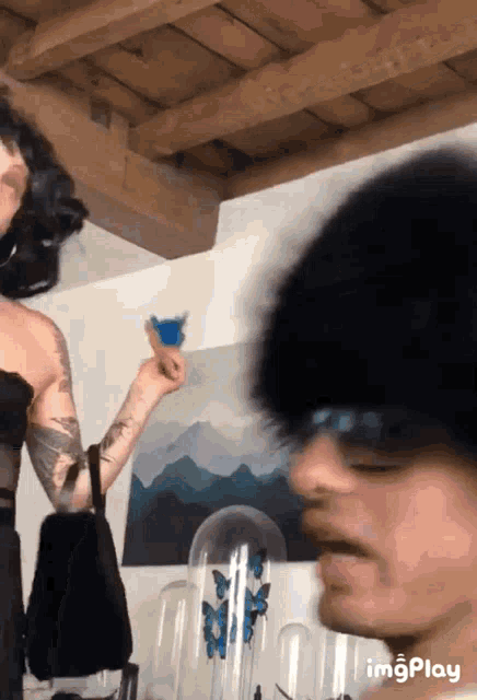 a woman holding a blue butterfly in front of a man wearing sunglasses and a hat
