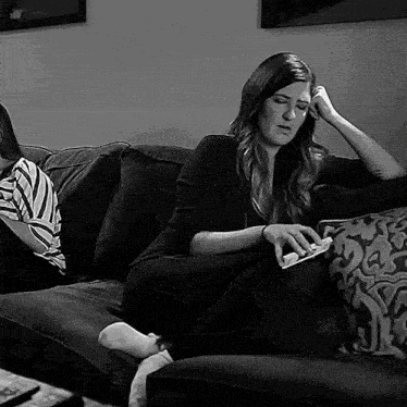 a woman is sitting on a couch with her legs crossed and a remote control in her hand .