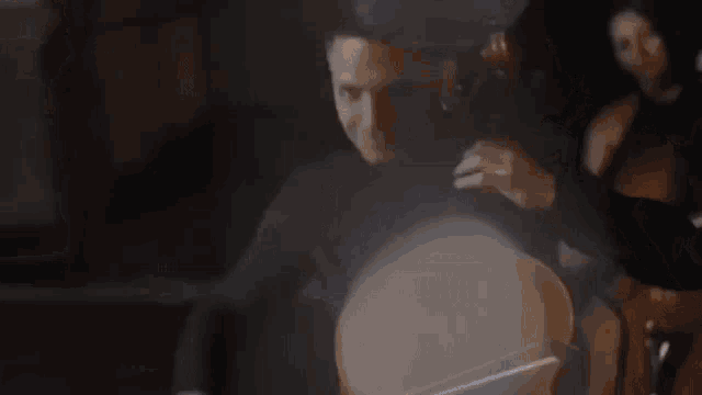 a man is playing a cello in a dark room while another man plays the cello in the background .
