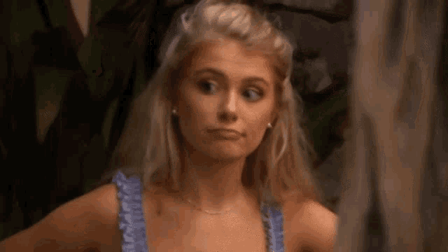 a woman in a purple tank top is making a funny face .