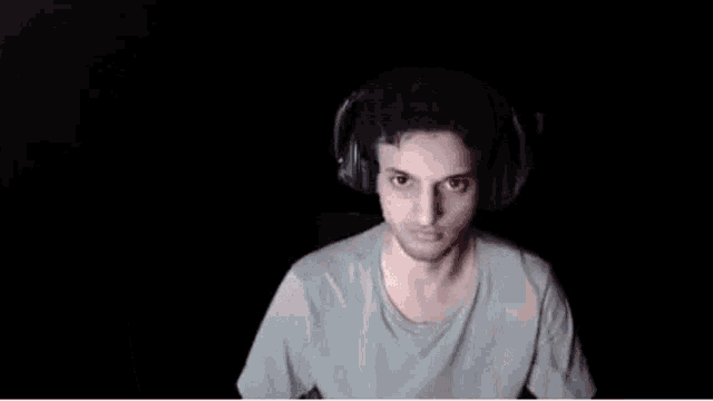 a man wearing headphones is flexing his muscles in front of a camera .