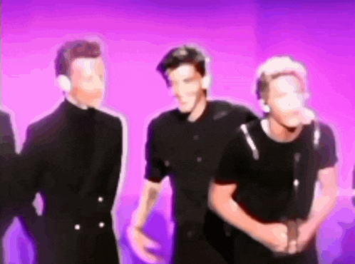 a group of men are standing next to each other in front of a purple wall .