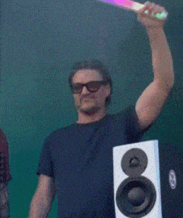 a man wearing sunglasses is holding a rainbow colored light up stick over his head
