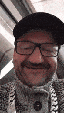 a man wearing glasses and a black hat is smiling