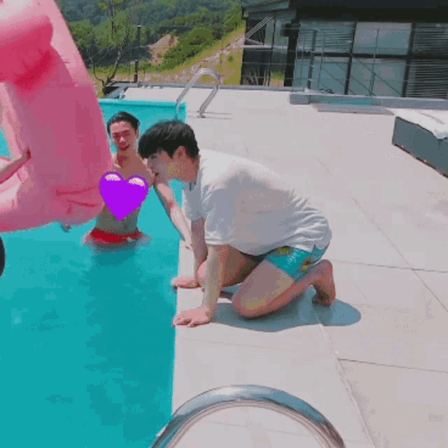 a man kneeling next to a swimming pool with a pink float in the background